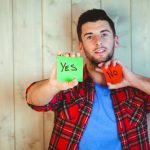 A young man holding up “yes” and “no” cards.