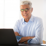 Older man smiles over his laptop