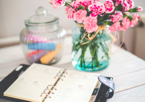 Vase of flowers blooms next to leather planner